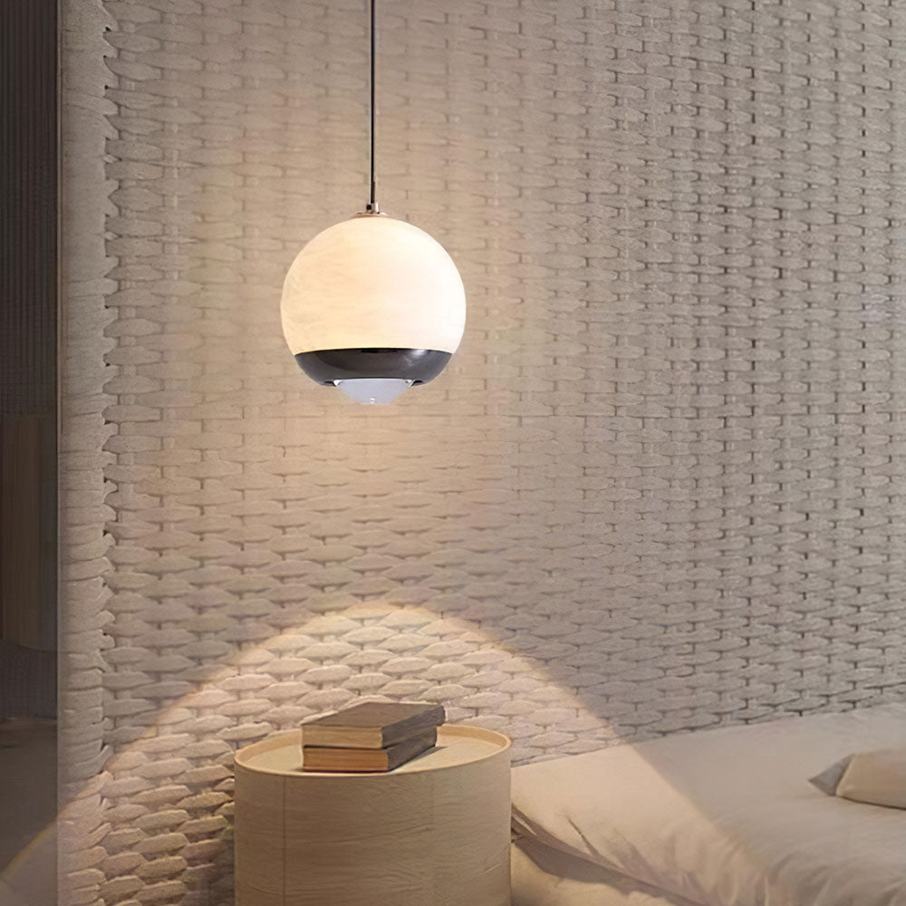 Minimalist 12cm alabaster mini pendant light with a black frame, glowing with integrated LED over a bedside table.