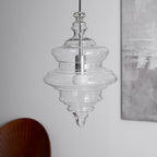 Sculptural clear glass pendant light with a tiered, theatre-inspired silhouette and a central white bulb.