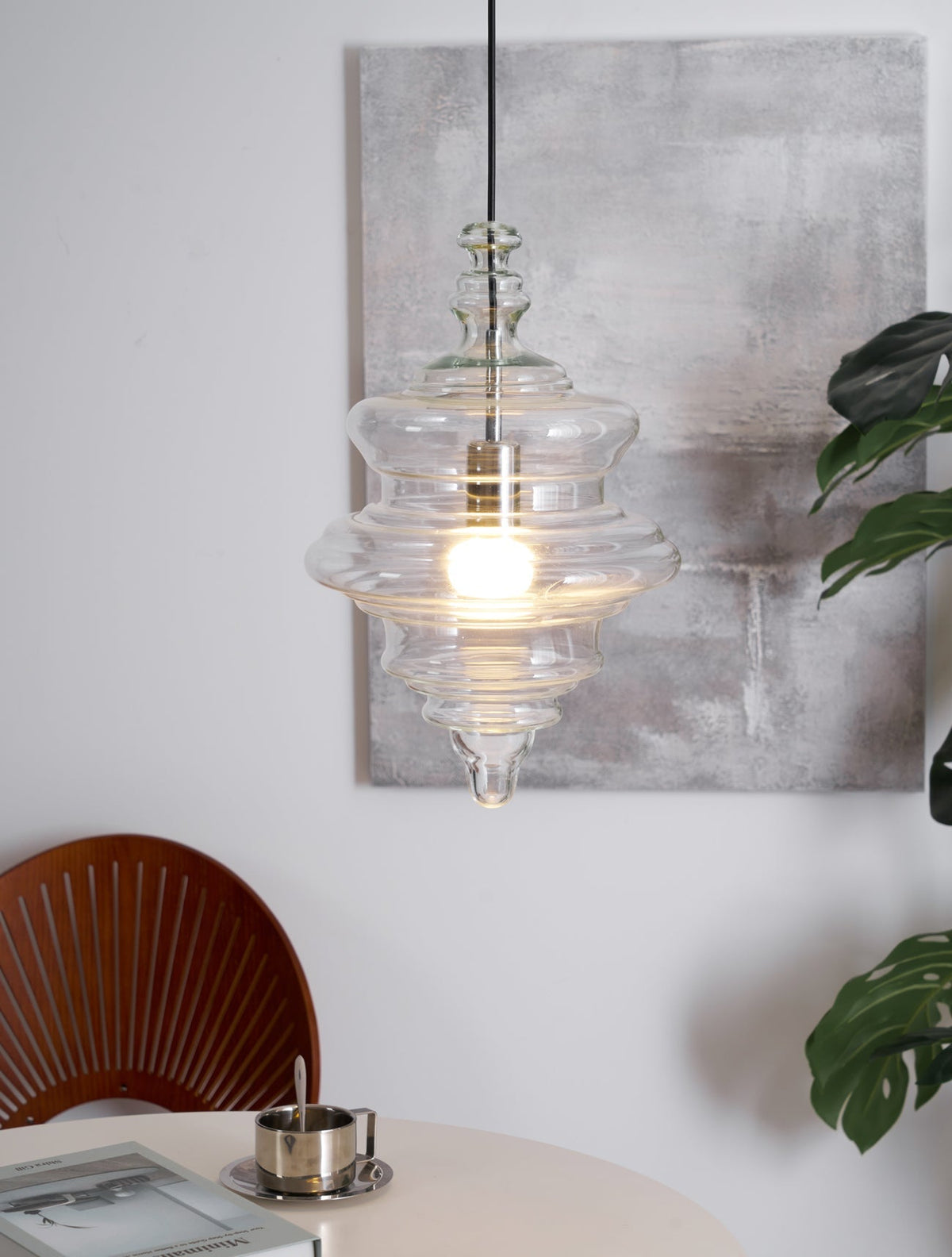 Sculptural clear glass pendant light with a rippled, theatre-inspired silhouette and warm filament bulb.