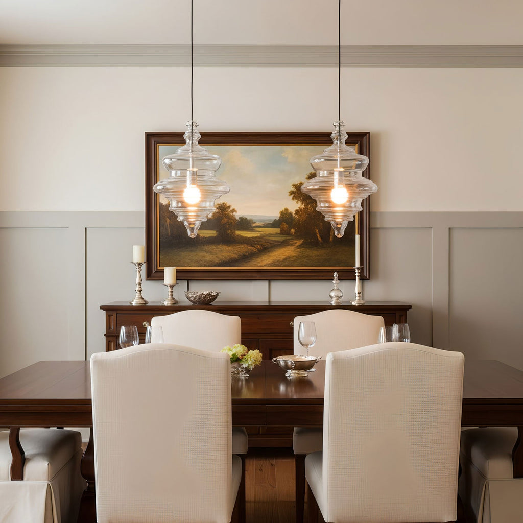 Two sculptural clear glass pendant lights with rippled textures hanging above a formal dining table.