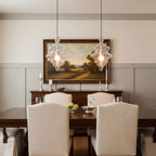 Two sculptural clear glass pendant lights with rippled textures hanging above a formal dining table.