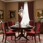 Sculptural clear glass pendant light with rippled texture hanging above a traditional dining table with red velvet chairs.