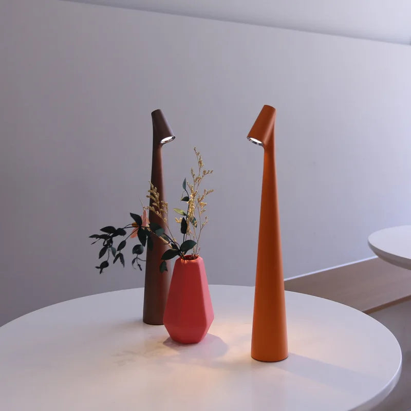 Slim, 33cm cordless LED table lamps in brown and orange on a white table next to a small pink vase.