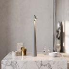 Minimalist grey cordless LED table lamp with a slim 33cm design, glowing on a white marble surface.