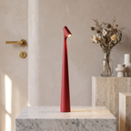 Slim red cordless LED table lamp with a minimalist 33cm tall design, glowing on a white marble pedestal.
