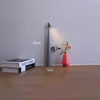 Slim grey cordless LED table lamp, 33cm tall with a minimalist design, glowing on a wooden surface next to books and a vase.