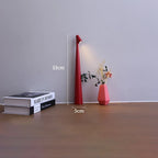 Slim red cordless LED table lamp, 33cm tall with a minimalist design, placed on a surface next to books and a small vase.