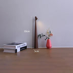 Slim brown cordless LED table lamp, 33cm tall with a minimalist design, placed on a surface next to books and a vase.