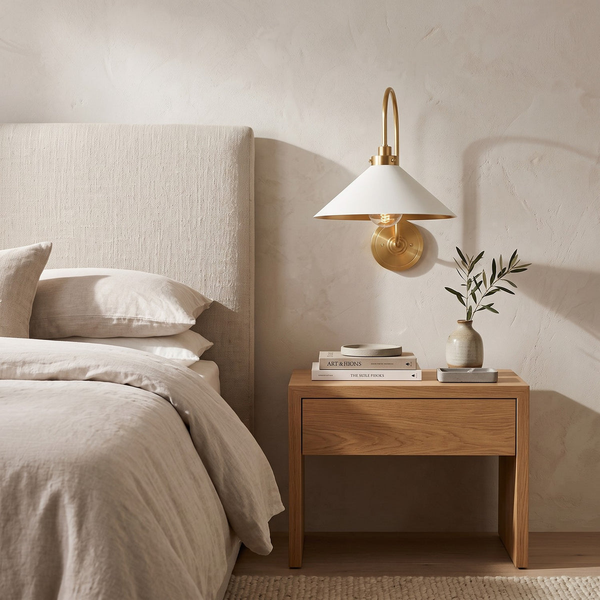 Curved Arm Cone Wall Light – Brass+White in a serene bedroom beside an upholstered headboard and oak nightstand