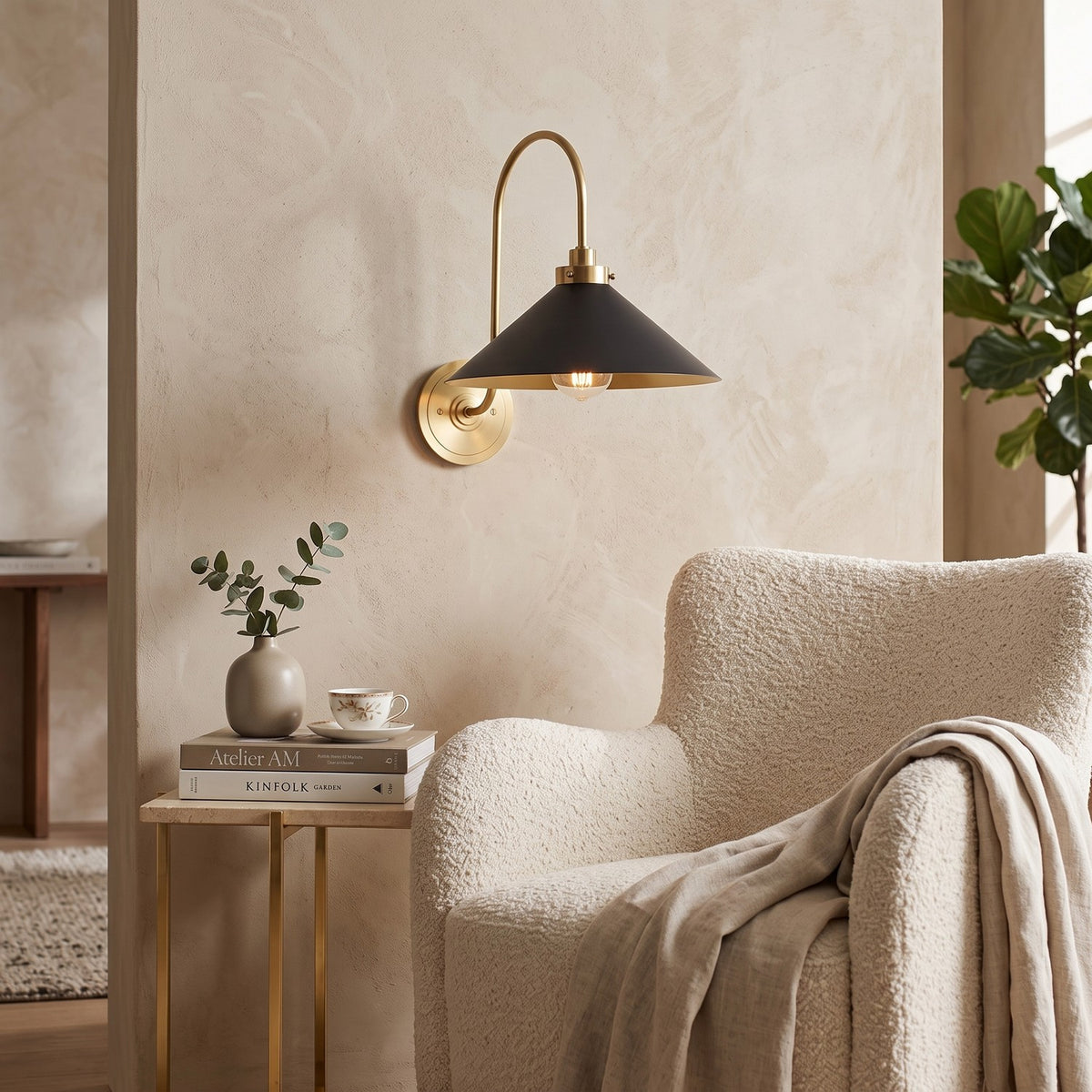 Curved Arm Cone Wall Light – Brass+Black in a quiet reading corner above a boucle armchair