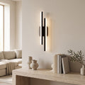 Geometric LED Wall Light – Black / Left in a bright living room above a travertine console