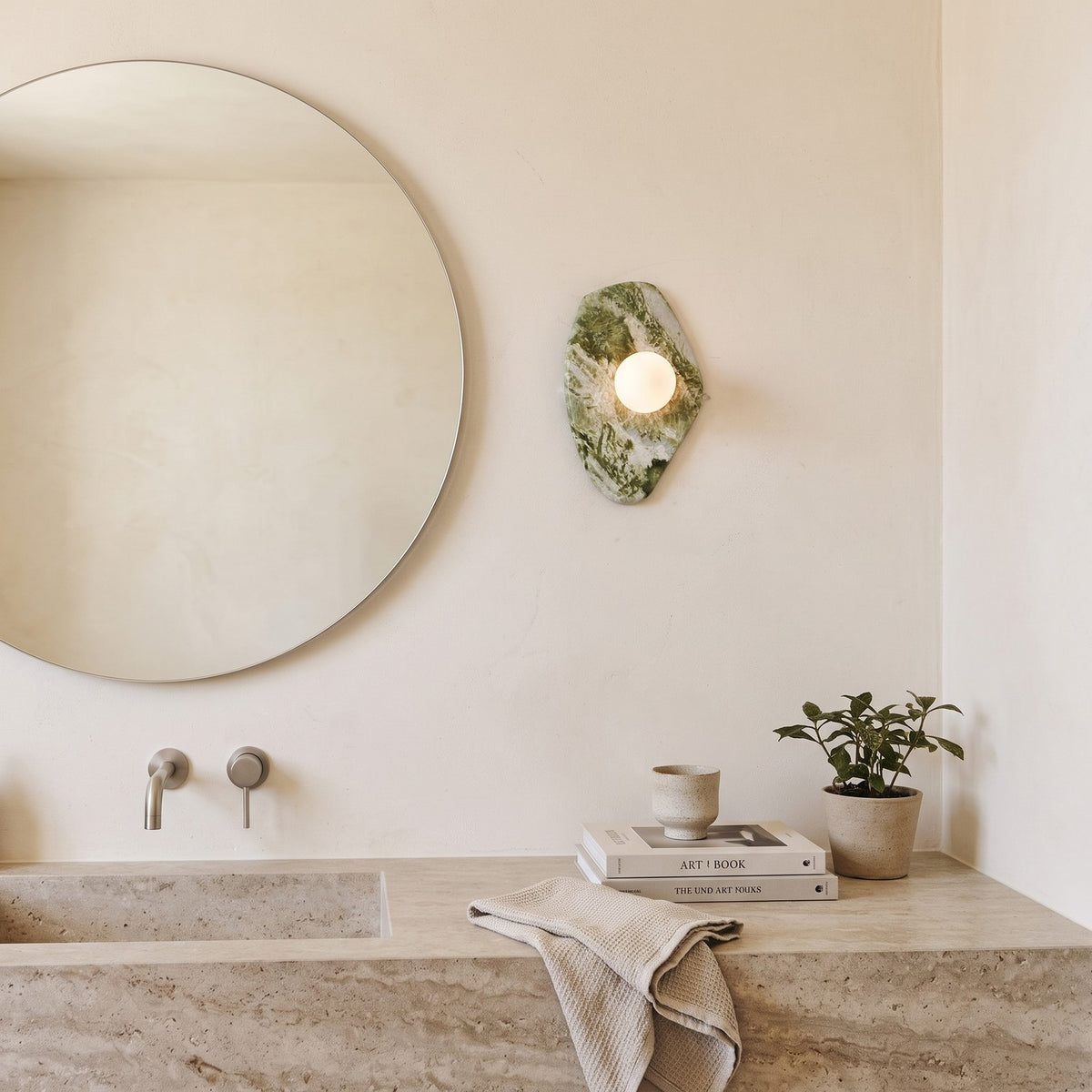 Green Marble Wall Light – Model A in a spa-like bathroom beside a large round mirror and stone vanity