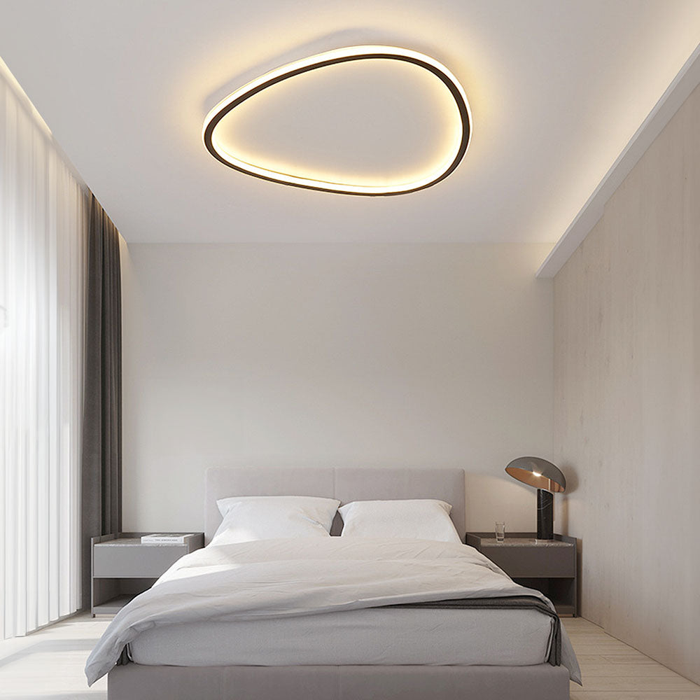 Minimalist black slim LED flush ceiling light with a soft, continuous glowing diffuser in a modern bedroom.