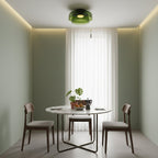 Retro green layered glass ceiling light fixture in a modern dining room with a marble table and wooden chairs.
