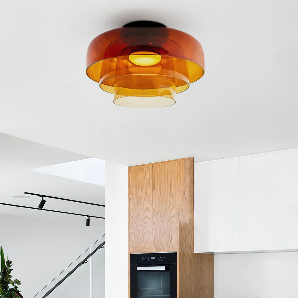 Retro layered ceiling light with orange stacked glass tiers emitting a warm, soft glow in a modern kitchen.