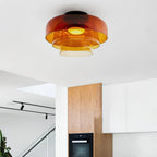 Retro layered ceiling light with orange stacked glass tiers emitting a warm, soft glow in a modern kitchen.