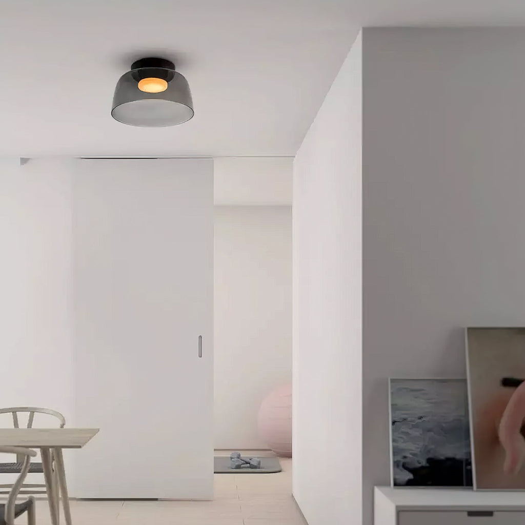 Retro layered smoky grey glass ceiling light emitting a warm glow in a modern minimalist interior.