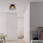 Retro layered smoky grey glass ceiling light emitting a warm glow in a modern minimalist interior.