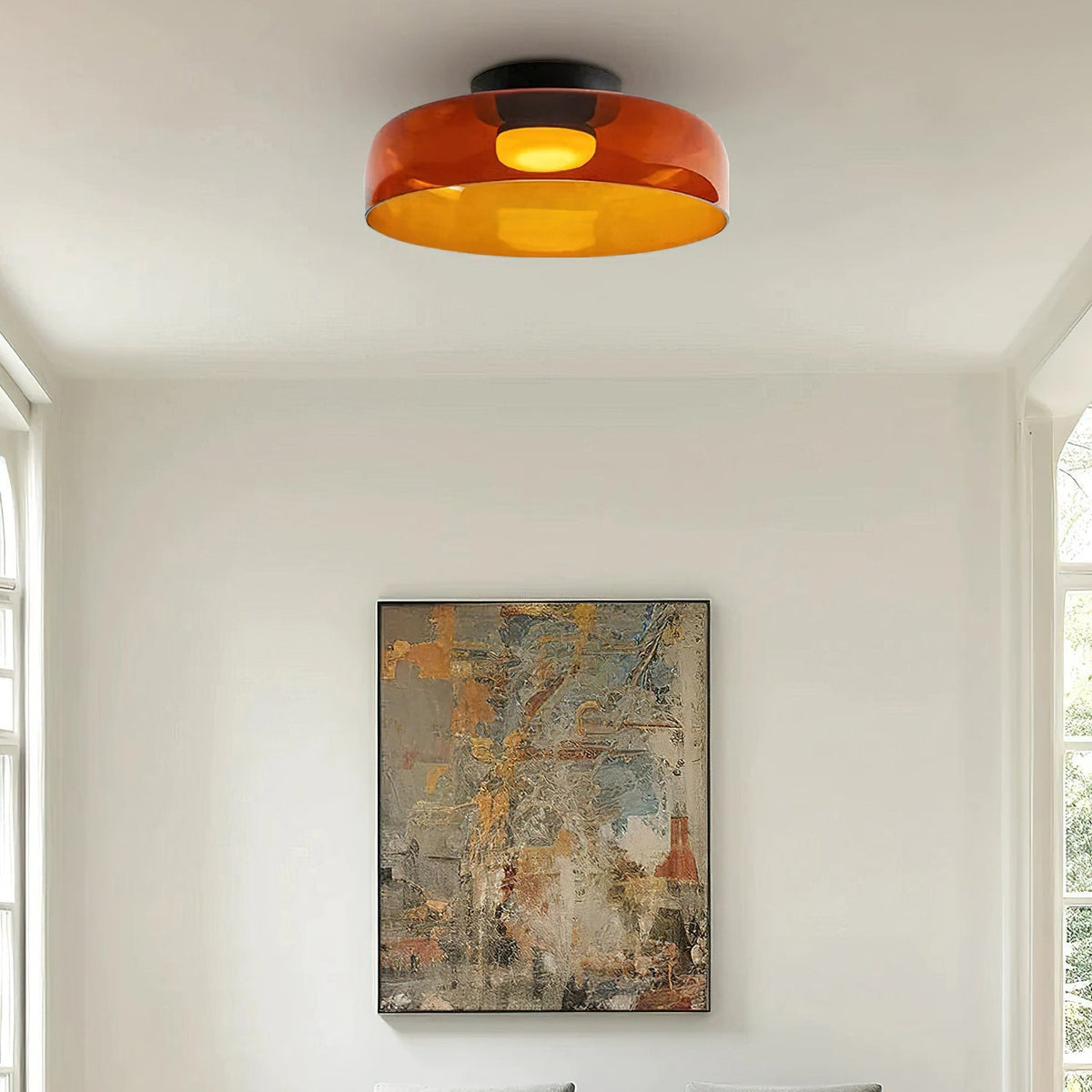 Retro orange layered glass ceiling light with a warm glow, mounted on a white ceiling above a framed abstract painting.