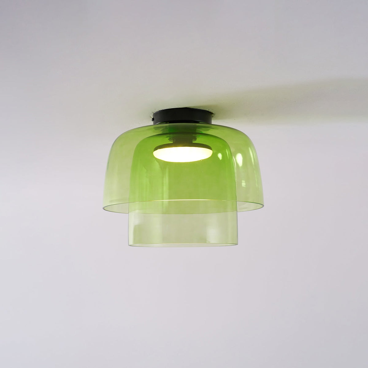 Retro layered green glass ceiling light with a stacked design and warm glowing center bulb.