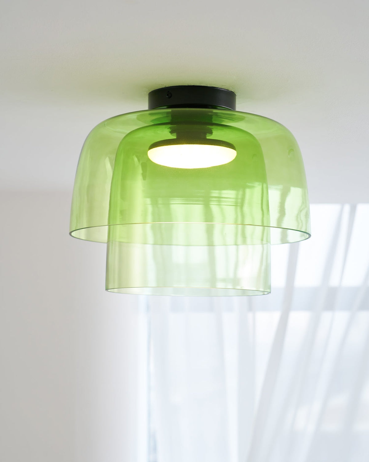 Retro layered green glass ceiling light with a stacked design and warm glowing center bulb.