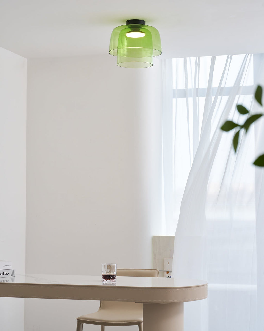 Retro layered green glass ceiling light with a stacked design, mounted above a modern dining table.