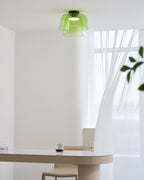 Retro layered green glass ceiling light with a stacked design, mounted above a modern dining table.