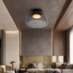 Retro ceiling light with a smoky grey glass dome and warm glowing center, mounted in a modern living room.