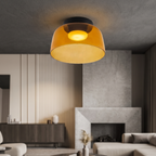 Retro layered orange glass ceiling light with a warm glow, mounted in a modern living room with a fireplace.