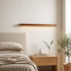 Linear Wood LED Wall Light – Brown in a serene bedroom beside an upholstered headboard and oak nightstand