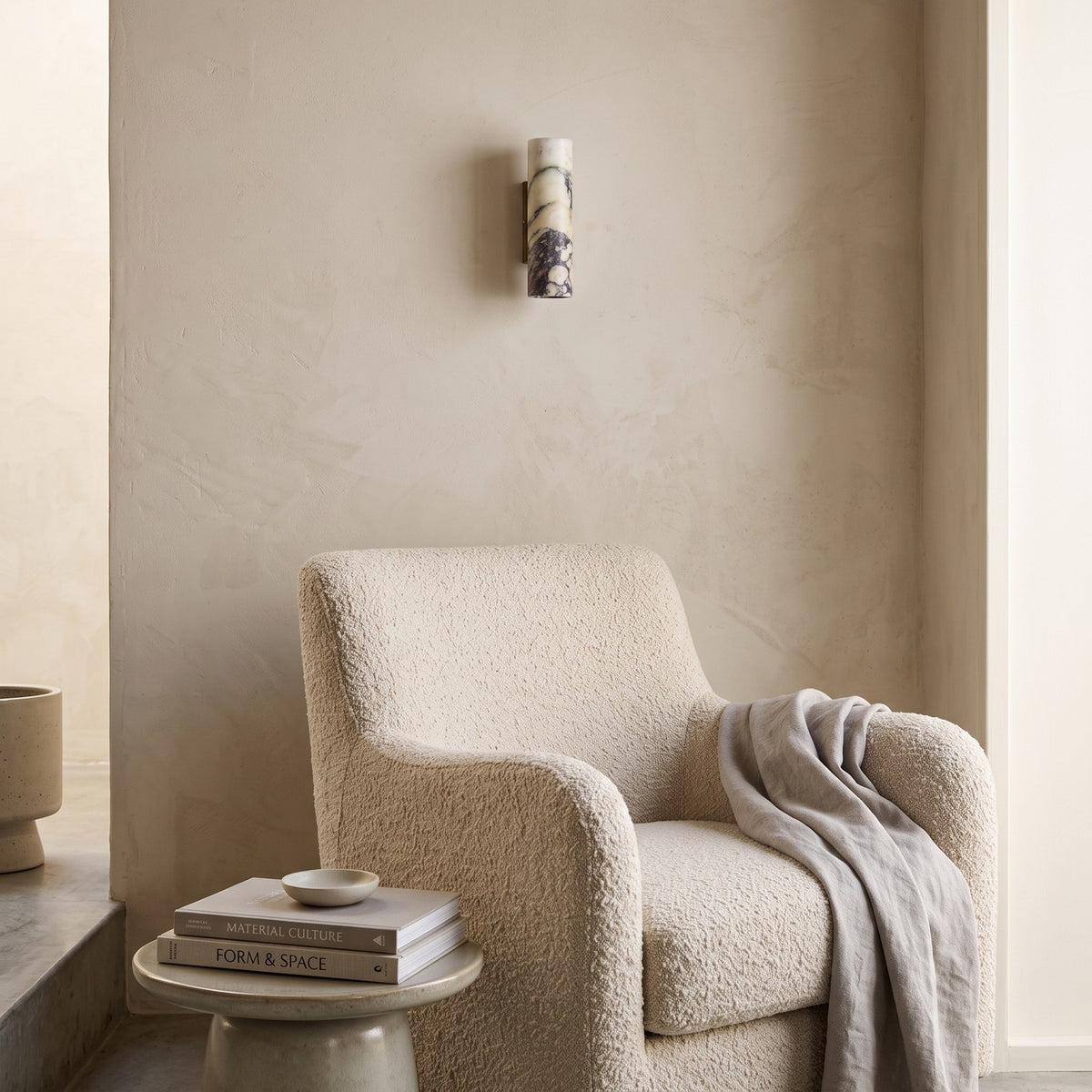 Marble Cylinder Wall Light – H 24cm in a quiet reading corner above a boucle armchair