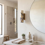 Marble Cylinder Wall Light – H 24cm in a spa-like bathroom beside a large round mirror and stone vanity