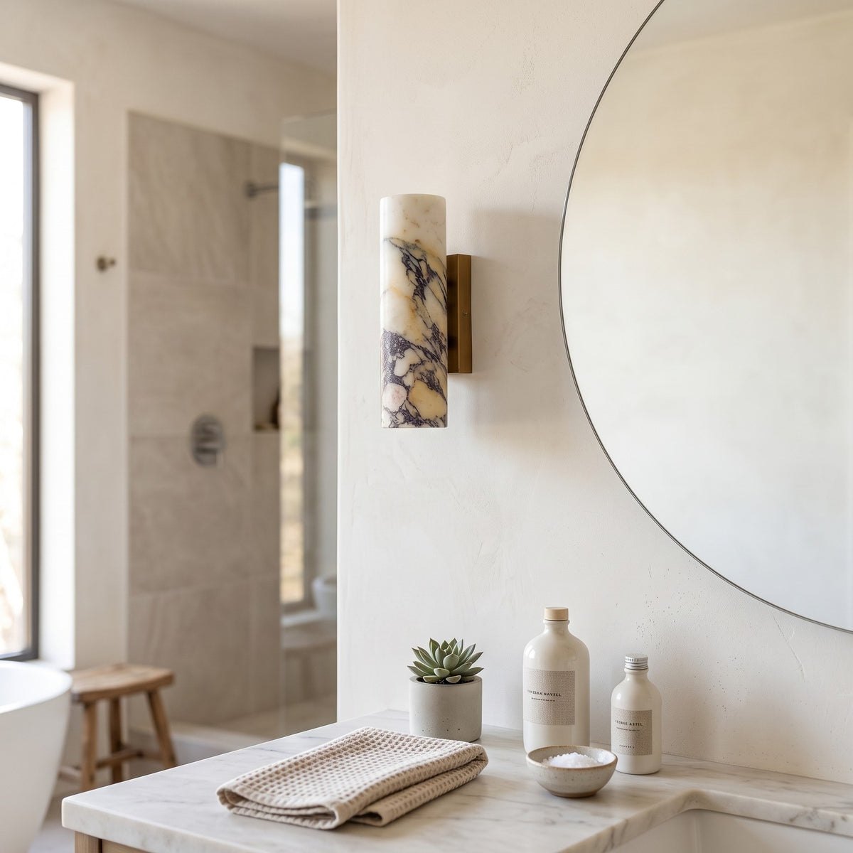 Marble Cylinder Wall Light – H 24cm in a spa-like bathroom beside a large round mirror and stone vanity