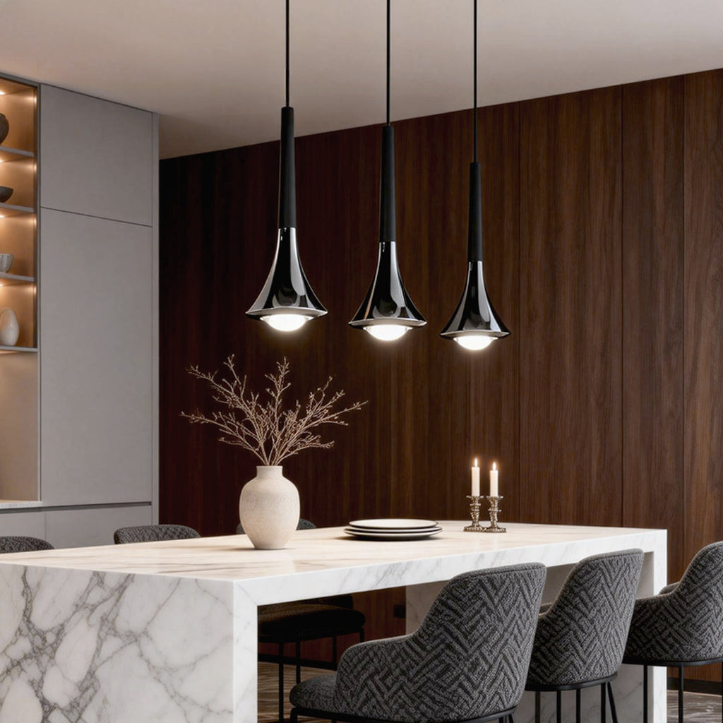 Three modern chrome and black teardrop LED pendant lights hanging over a marble dining table.