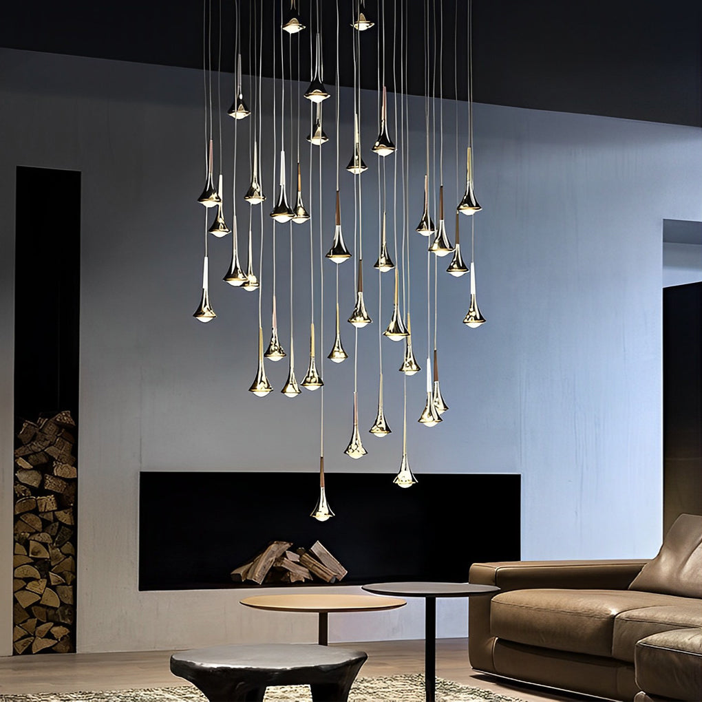 Modern gold teardrop LED pendant light cluster hanging in a contemporary living room with a fireplace.