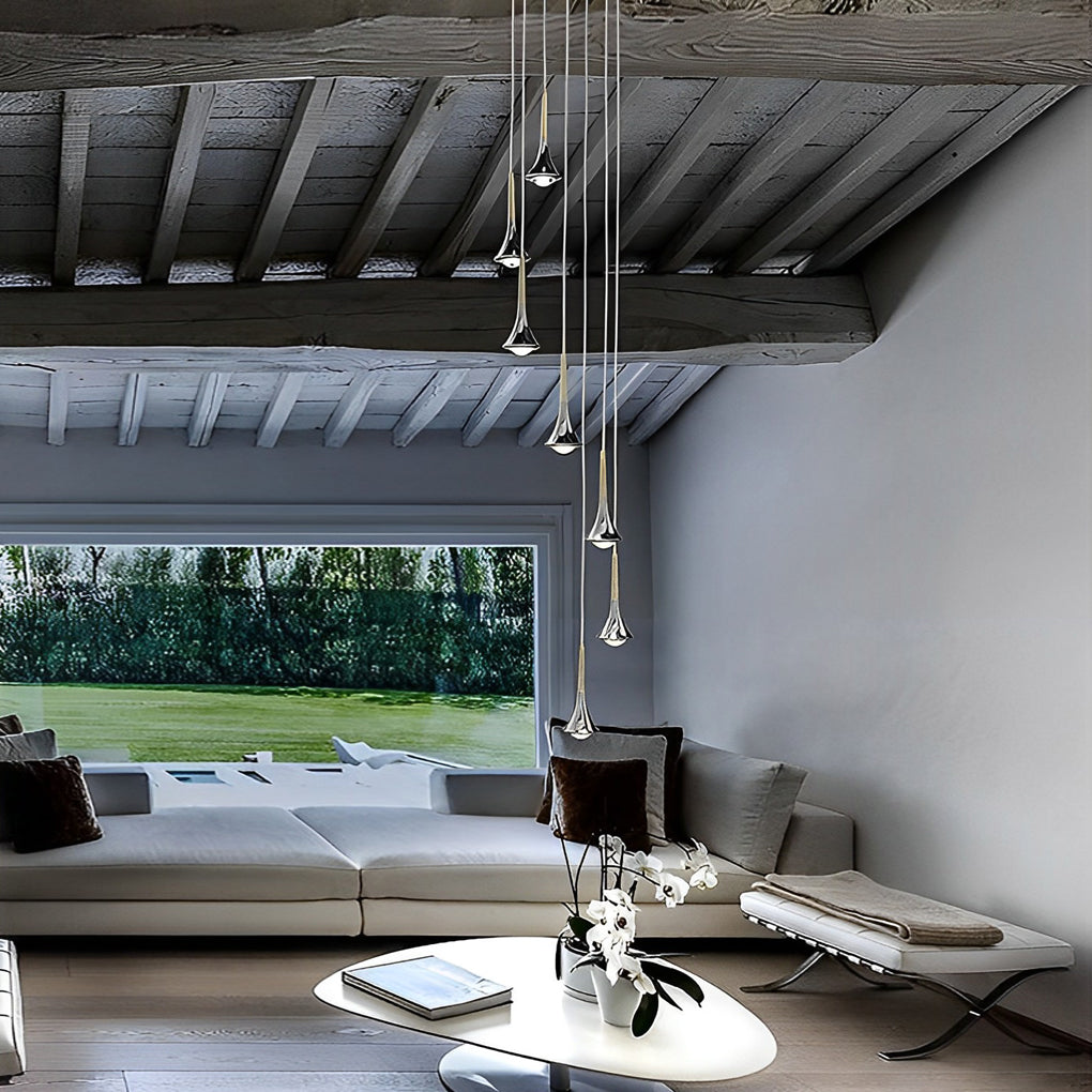 Modern chrome teardrop LED pendant lights hanging in a cluster above a contemporary living room sofa.