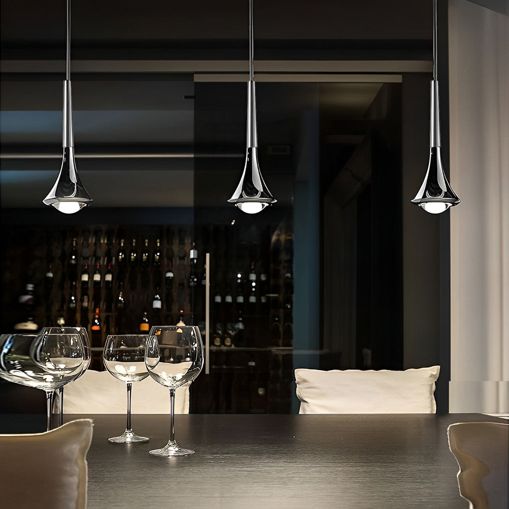 Three modern chrome teardrop pendant lights with focused LED downlighting hanging over a dining table.
