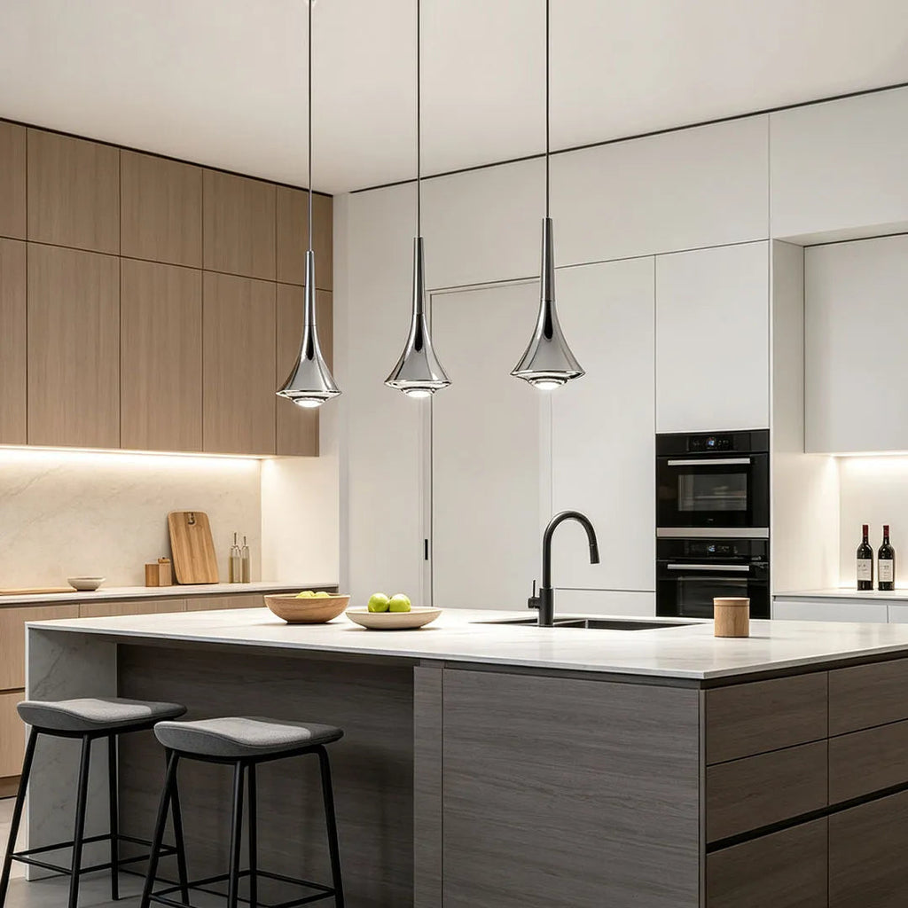 Three modern chrome teardrop pendant lights hanging over a kitchen island with a sleek, minimalist design.