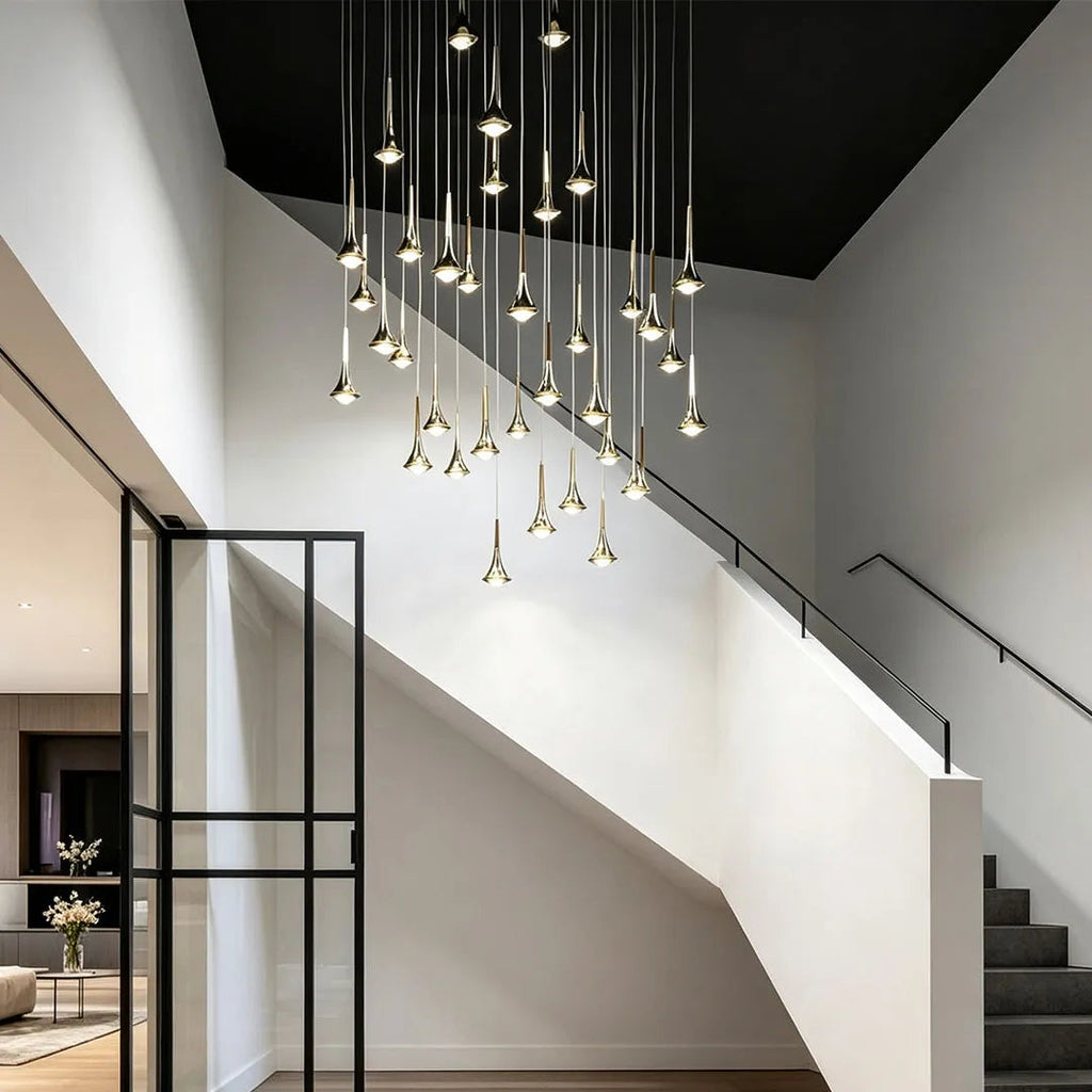 Modern gold teardrop LED pendant lights hanging in a cluster above a contemporary staircase.