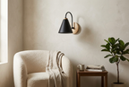 Nordic Wood Wall Light in black above an armchair in a reading corner