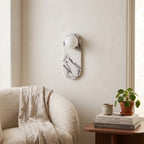 Oval Marble Wall Light – White in a quiet reading corner above a boucle armchair