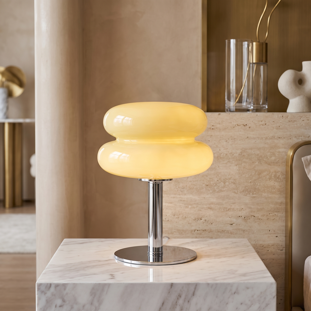 Retro yellow glass table lamp with a rounded, tiered shade on a polished chrome base sitting on a marble surface.