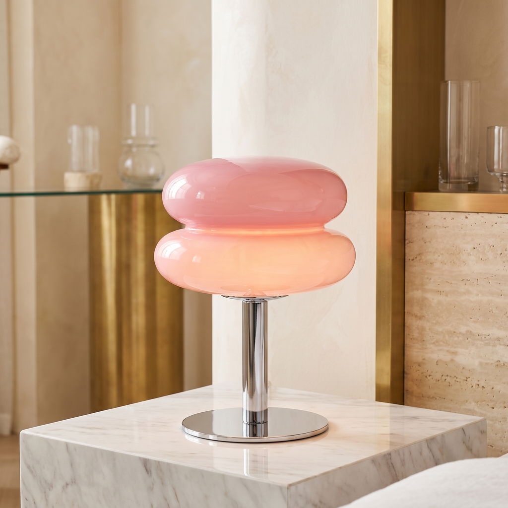 Retro pink glass table lamp with a rounded, tiered shade on a polished chrome base, sitting on a marble surface.