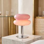 Retro pink glass table lamp with a rounded, tiered shade on a polished chrome base, sitting on a marble surface.