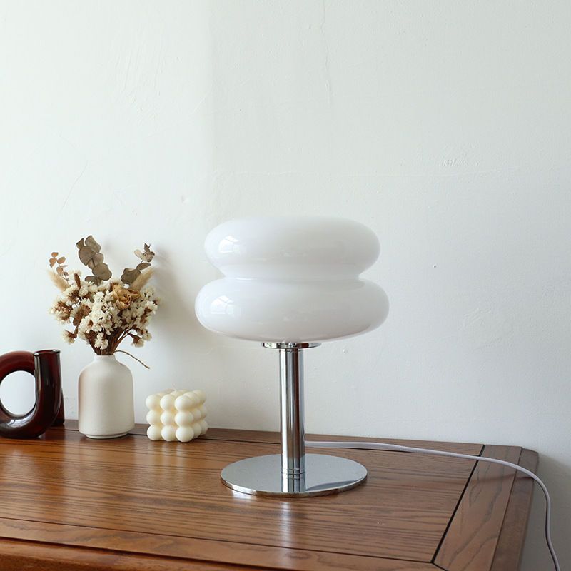 Retro 70s space age table lamp with a white rounded glass shade and a polished chrome base on a wooden surface.