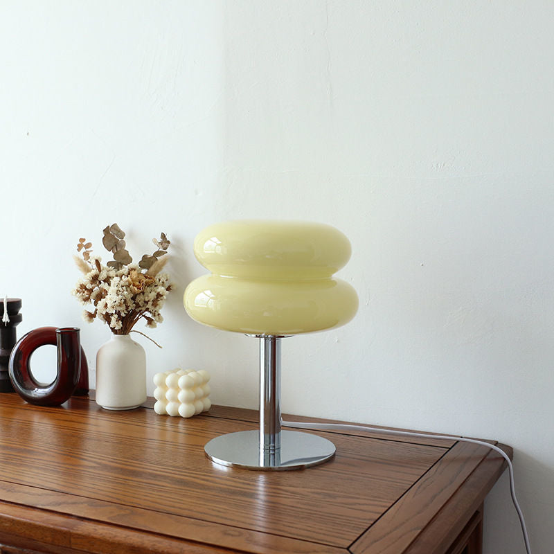 Yellow retro space age table lamp with a rounded glass shade and polished chrome base on a wooden surface.