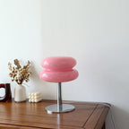 Pink retro space age table lamp with a rounded glass shade and polished chrome base on a wooden surface.
