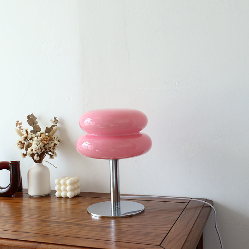 Pink retro space age table lamp with a rounded glass shade and polished chrome base on a wooden surface.