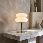 Retro 70s space age table lamp with a glowing white glass shade and polished chrome base on a marble surface.