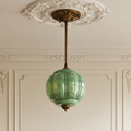 Vintage green sculpted glass semi-flush ceiling light with antique brass hardware in a classic period-style room.